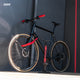 AARON Sport One Fahrradpumpe - Rot neben schwarzem Fahrrad mit roten Griffen und Pumpe an Wand stehend