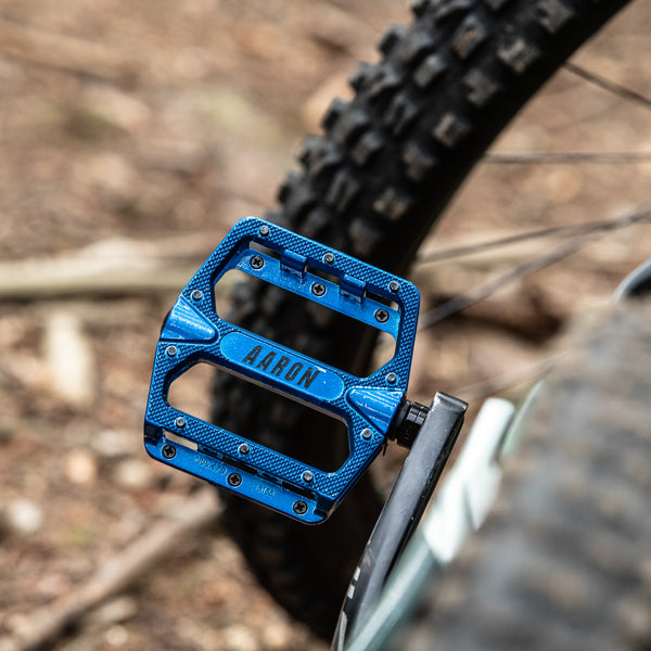 AARON Rock MTB Pedale - Blau aus Aluminium mit geriffelter Plattform und austauschbaren Pins am Mountainbike montiert.