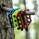 AARON Rock MTB Pedale - Blau, gelb und rot, hochwertige Aluminium Mountainbike Pedale mit austauschbaren Pins am Baum angebracht.