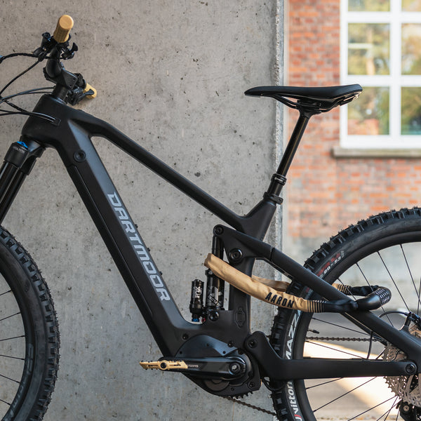 AARON Dirt MTB Fahrradpedale - Beige montiert an schwarzem Mountainbike vor grauer Wand und Fenster im Hintergrund.