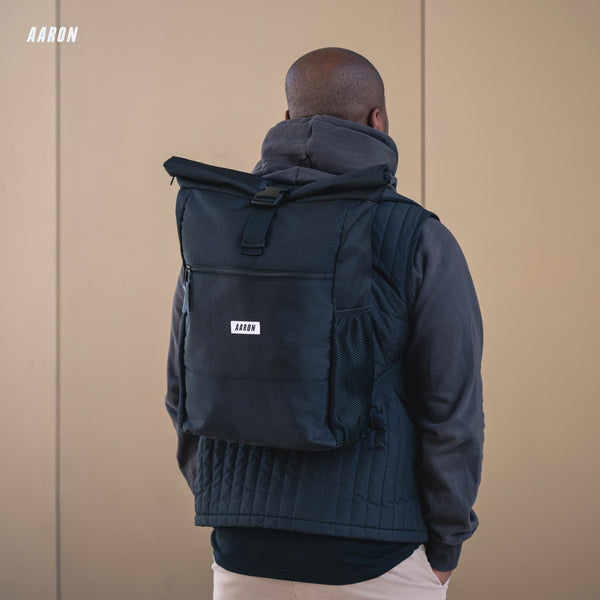 AARON Rolltop Rucksack für Damen und Herren - Schwarz am Rücken eines Mannes