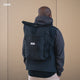 AARON Rolltop 2.0 Rucksack für Damen und Herren - Schwarz am Rücken eines Mannes