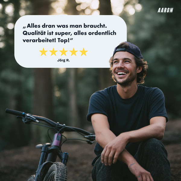Junger Mann sitzt lächelnd neben Mountainbike mit AARON Peak - MTB, Enduro & BMX Fahrradgriffe - Mint im Wald.