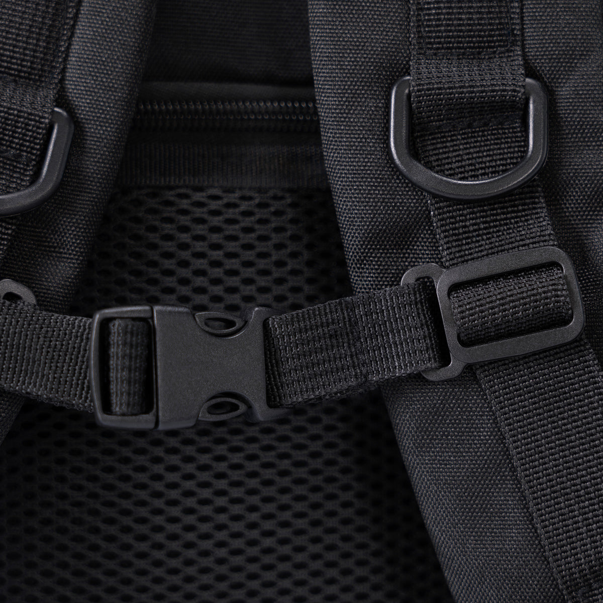 Nahaufnahme eines schwarzen Rucksacks mit verstellbaren Nylongurten, Kunststoffschnallen und Netzpolsterung auf dem Rücken für zusätzlichen Komfort und Belüftung.